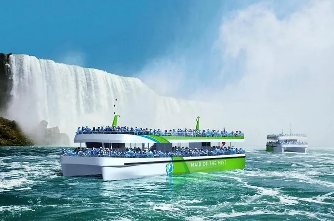 Two Maid of the Mist boats on green water below a wide curtain of falls
