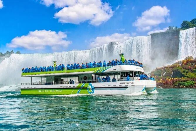 Ein Boot der Maid of the Mist mit Passagieren in blauen Ponchos unterhalb der Fälle
