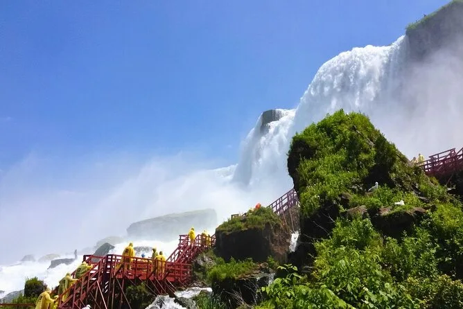Nasse rote Holztreppen über moosigem Fels neben einem Wasserfall