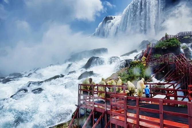 Visitors in yellow ponchos on red wooden decks beside white water below the falls
